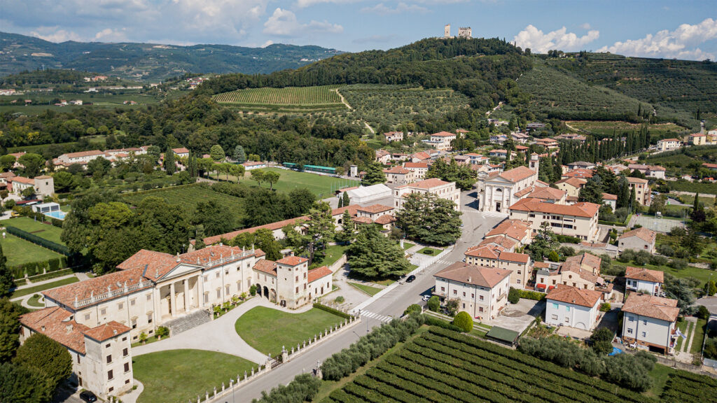 Illasi, veduta aerea del centro storico del paese con villa storica, chiesa e castello sulla collina